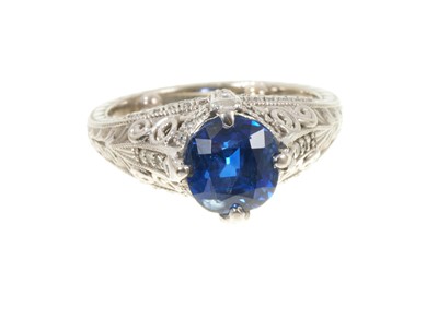 Lot 719 - Fine sapphire single stone ring with a natural cushion cut blue sapphire weighing 2.66ct in four claw setting with pavé set diamonds to the claws and bezel and pierced decoration on engraved s...