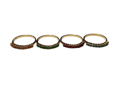 Lot 313 - Set of four 9ct gold gem set half eternity rings, each band set with a line of ten round cut stones in blue, yellow, green and red