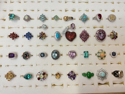 Lot 126 - Collection of 34 contemporary silver multi-gem set dress rings in a ring display case