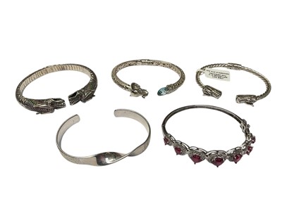 Lot 132 - Five contemporary silver bangles to include two dragon torque bangles, a similar style elephant bangle, gem set heart bangle and one other torque bangle (5)