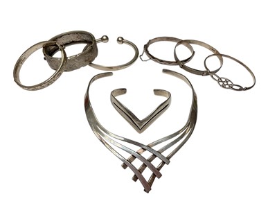 Lot 135 - Modernist style silver torque necklace, a similar torque bangle, 1950s/60s and later silver bangles and one white metal bangle with engraved decoration (8)