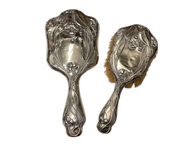 Lot 184 - Art Nouveau silver backed dressing table mirror and brush, both with embossed floral decoration