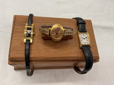Lot 949 - Ladies Gucci gold plated wristwatch, 3900L, on black leather strap, and two other ladies wristwatches in a wooden box (3)