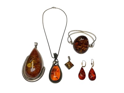 Lot 231 - Group of silver mounted amber jewellery to include a bangle, three pendants, one with a silver chain and a pair of earrings with gilt metal fittings