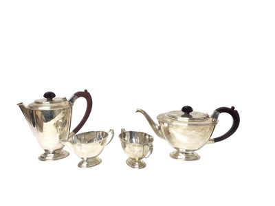 Lot 305 - Elizabeth II silver three piece teaset, comprising teapot of oval form, with ebonised wood finial and handle, raised on an oval foot, together with matching hotwater pot, milk jug and sugar bowl...