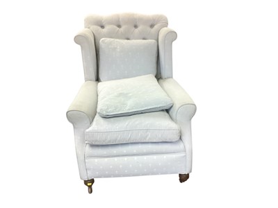 Lot 1407 - Edwardian buttoned back wing easy chair with loose cushions, upholstered in patterned light blue fabric, on turned legs and castors