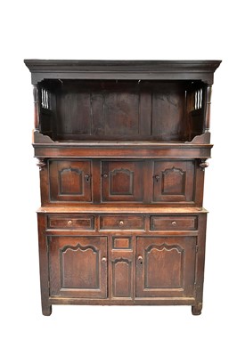 Lot 1305 - Early 18th century Welsh oak tridarn, with upper open canopy and three fielded recessed panelled doors below, the central door enclosing short drawers, the base with twin cupboards and conformin...