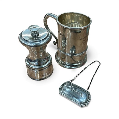 Lot 969 - 1920s silver christening mug, silver pepper grinder and silver whisky label (3)
