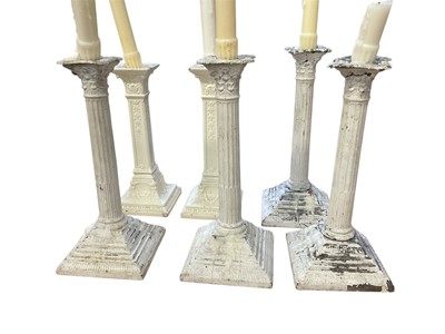 Lot 152 - Set of four white painted metal Corinthian column candlesticks and a pair of similar ceramic sticks