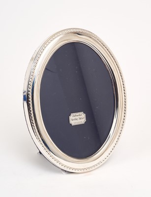 Lot 209 - Contemporary silver photograph frame of oval form, with ropework border and blue velvet easel back