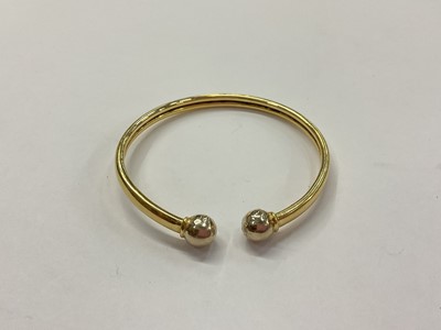 Lot 963 - Yellow metal torque bangle with applied plague marked ‘18ct’