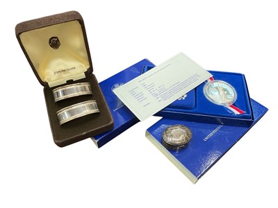 Lot 910 - Small group of silver including two mint American dollars, cased napkin rings and small pill box.