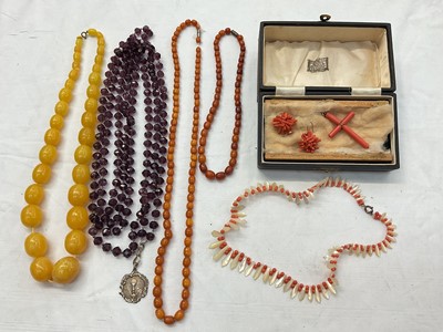 Lot 946 - Antique coral cross pendant, pair of coral cluster earrings, coral and mother of pearl fringe style necklace, two vintage amber bead necklaces, simulated amber necklace and a long purple faceted...