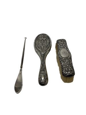 Lot 240 - Late Victorian silver mounted hairbrush with floral decoration and engraved initials (Birmigham 1902), together with an early twentieth century silver mounted hair brush with Art Nouveau decora...