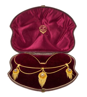 Lot 400 - Victorian Etruscan Revival gold necklace, the three circular target shaped pendant drops each with a central seed pearl, blue enamel stars and articulated tassels suspend from three buckles on s...