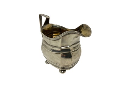 Lot 346 - George V silver cream jug of helmet form, with reeded border and gilded interior, raised on four bun feet, (Chester 1914), maker George Nathan & Ridley Hayes, 10cm in overall height, all at 4.6ozs.