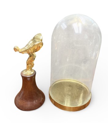 Lot 12 - Rolls-Royce Silver Shadow II gold plated Spirit of Ecstasy mascot with spring movement on turned mahogany display plinth under glass dome with gilt metal base. The mascot 10cm high. The dome 26....