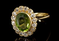 Lot 530 - Peridot and diamond cluster ring, the oval...