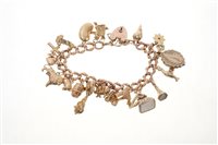 Lot 505 - Gold charm bracelet with a collection of gold...