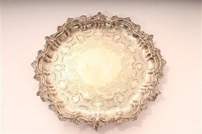 Lot 444 - Late Victorian silver salver of circular form, with engraved scroll and foliate decoration and scroll, shell and foliate border, on three shell and foliate feet