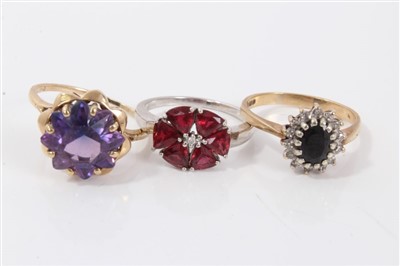 Lot 3229 - Two gold (9ct) gem set dress rings and a white gold (9ct) red stone flower head dress ring. (3)