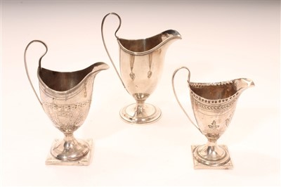 Lot 357 - Three George III silver helmet shaped cream jugs