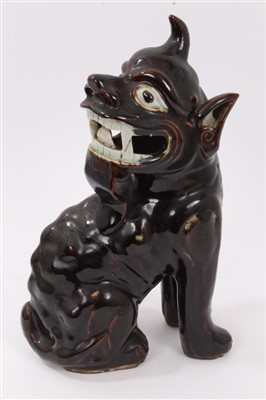 Lot 256 - 19th century Chinese brown treacle glazed figure of a temple dog seated looking rearward, 33cm