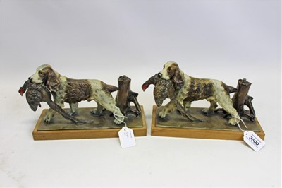 Lot 3500 - Pair Austrian cold-painted spelter table lighters in the form of spaniels carrying a cock pheasant near a tree stump, on wooden bases, 27cm overall length