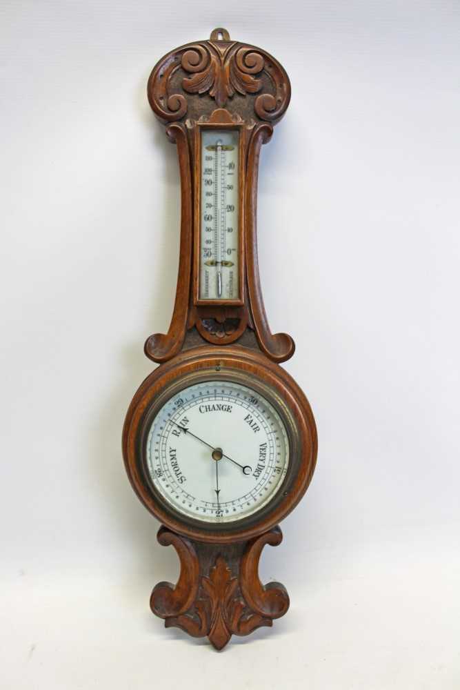 Lot 3505 - Early 20th century aneroid barometer with 5 inch circular dial and separate thermometer in a carved oak case, 60cm overall length