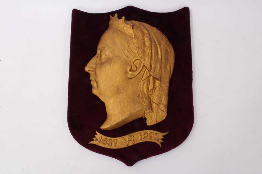 Lot 130 - Victorian Diamond Jubilee 1897 gilt metal relief plaque by Kenrick & Son, with profile portrait of The Queen and scroll ‘1837 VR 1897’, mounted on red velvet covered shield, 35cm