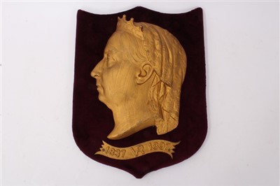 Lot 130 - Victorian Diamond Jubilee 1897 gilt metal relief plaque by Kenrick & Son, with profile portrait of The Queen and scroll ‘1837 VR 1897’, mounted on red velvet covered shield, 35cm