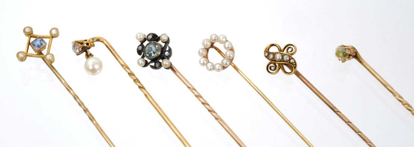 Lot 565 - Six Edwardian stick pins – to include an aquamarine, diamond and seed pearl stick pin, pale-yellow old cut diamond stick pin and four others