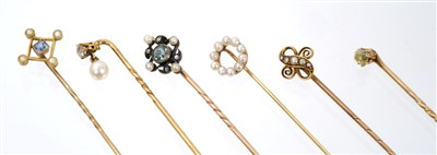 Lot 565 - Six Edwardian stick pins – to include an aquamarine, diamond and seed pearl stick pin, pale-yellow old cut diamond stick pin and four others