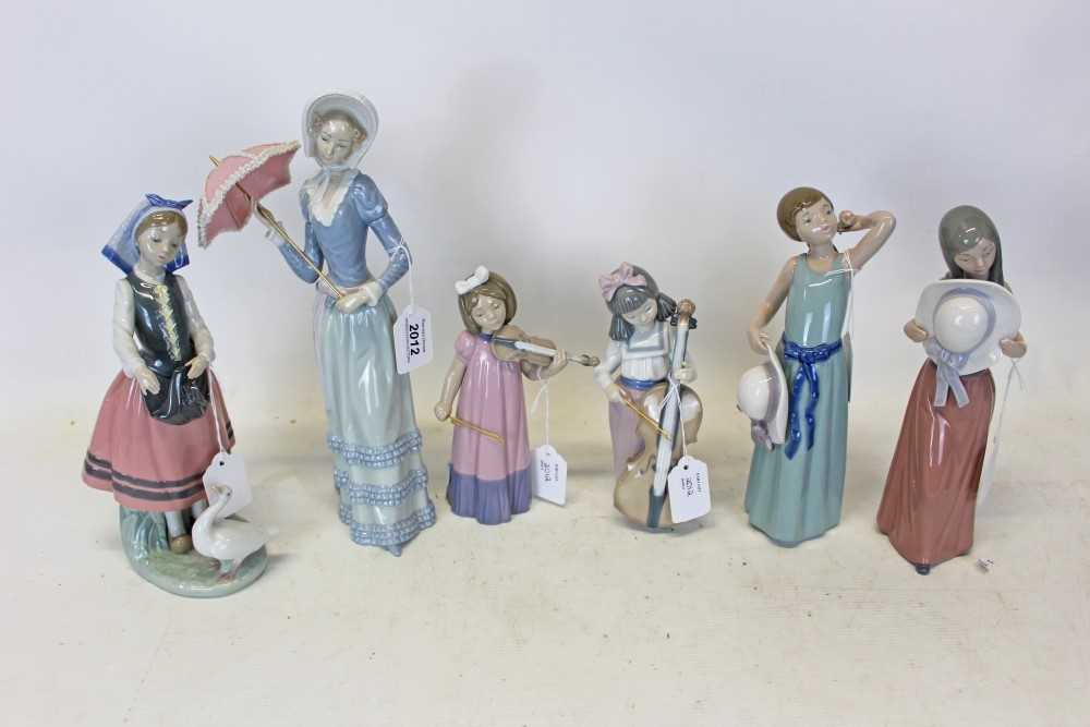 Lot 2012 - Four Lladro porcelain figures, women holding an umbrella, young girl feeding a goose, two girls holding there hats together with two Nao figures, young musicians (6)