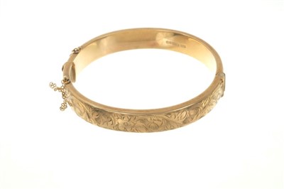 Lot 480 - Gold (9ct) bangle with engraved floral scroll decoration, 18cm