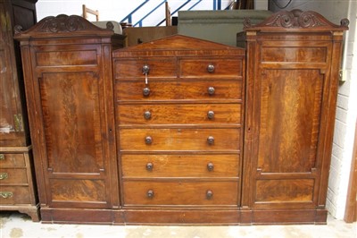 Lot 1354 - William IV mahogany compactum wardrobe with arched central section having two short over five long graduated drawers, flanked by pair of panelled doors below anthemion carved scrolled cresting, rai...