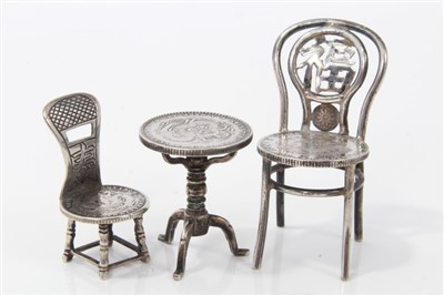 Lot 2727 - Antique Chinese miniature silver chair, with pierced back, a Kwang Tung Province coin forming the seat, 5cm high, character marks to rear, together with a similar smaller chair and tripod table