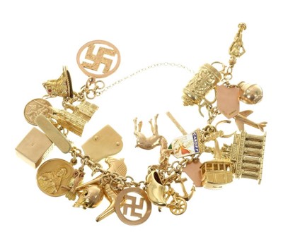 Lot 462 - Gold charm bracelet with a collection of gold and yellow metal charms, 79 grams.