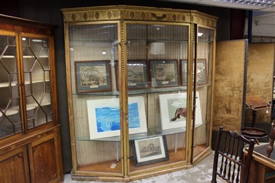 Lot 1390 - Louis XVI style giltwood display cabinet, of canted outline, with boss and fluted frieze, enclosed by three glazed doors on plinth base, 230cm wide x 28cm deep x 218cm high