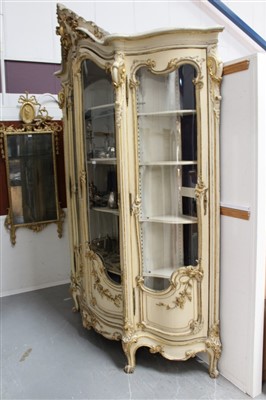 Lot 1391 - Impressive late 19th / early 20th century Rococo cream and gilt painted display cabinet, of serpentine outline, enclosed by pair of shaped doors and glazed sides, applied with gilt floral carved sw...