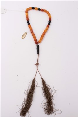 Lot 3409 - Old Chinese amber bead necklace with a string of amber beads interspaced by darker beads, with silk tassel.