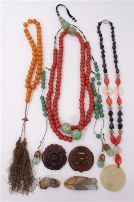 Lot 3412 - Three old Chinese necklaces two include a coral glass bead and green stone necklace, simulated amber bead necklace, hardstone necklace with carved jade/hardstone disc and four carved hardstone carv...