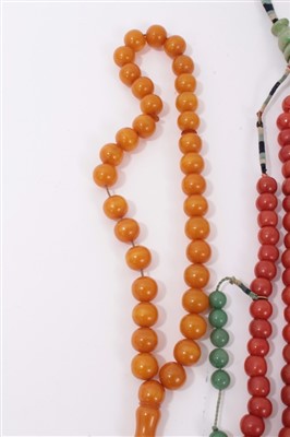 Lot 3412 - Three old Chinese necklaces two include a coral glass bead and green stone necklace, simulated amber bead necklace, hardstone necklace with carved jade/hardstone disc and four carved hardstone carv...