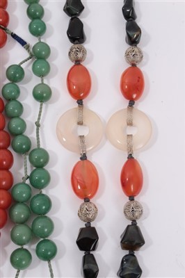 Lot 3412 - Three old Chinese necklaces two include a coral glass bead and green stone necklace, simulated amber bead necklace, hardstone necklace with carved jade/hardstone disc and four carved hardstone carv...