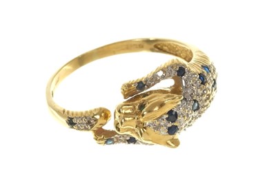 Lot 556 - Diamond and blue sapphire dress ring modelled as a leopard with emerald eyes, finger size Q1/2.