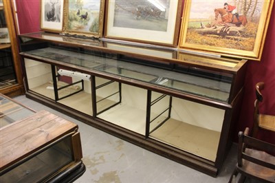 Lot 1444 - Very large early 20th century shop counter, the upper section accessed by four rear hinged doors, the base with four glazed doors, 322cm wide x 59cm deep x 105cm high