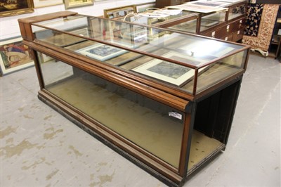 Lot 1445 - Early 20th century shop counter, with angled end, the glazed top with three rear hinged doors, the glazed base with panelled back, 224cm wide x 60cm deep x 101cm high