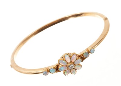 Lot 632 - Edwardian opal and diamond hinged bangle, the flower head cluster with a central old cut diamond, cabochon opal petals and further opals to the shoulders.