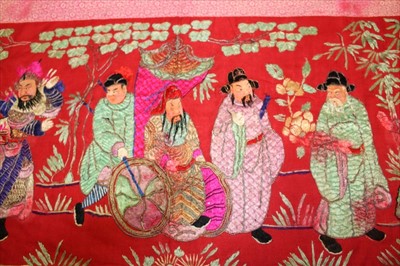 Lot 3054 - Chinese embroidered red silk banner. Silk satin stitch with crouched outlines, figures have painted silk faces, Wiseman in sedan chair, dancers and deities in garden scene. Printed cotton lining
