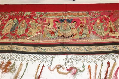 Lot 3056 - Chinese embroidered red silk banner.  Officials, deities and Gods in garden scene with pagoda and monkey holding a peach. Forbidden knot embroidered edging. Red cotton lining, knotted fringing with...